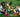 Three children building with colorful jumbo building blocks on green grass.