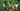 Three children building with colorful jumbo building blocks on green grass. 
