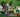 Three children building with colorful jumbo building blocks on green grass. 