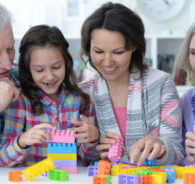 Grandparents and grandchildren bond over creative play with building blocks, sharing smiles and stories while stacking colorful blocks together.