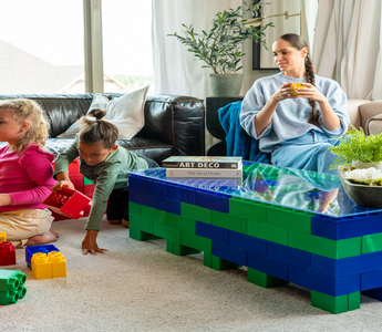 Three young children sitting on the floor, engaging in creative play with colorful building blocks in a cozy living room setting.