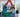 A mother and her two children engage in imaginative play at home, using large Biggo Blocks to construct a colorful playhouse or shop. One child, dressed as a chef, pretends to serve food through a window, creating a playful and creative moment.