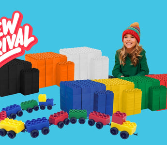 A colorful arrangement of new orange, black, and white Biggo Blocks, with a child seated beside the blocks. The display also features various single color sets and train sets, promoting the new product arrivals from Biggo Blocks.