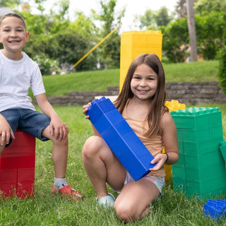 A boy and a girl happily enjoying playing outdoors with colorful jumbo building blocks from Biggo Blocks