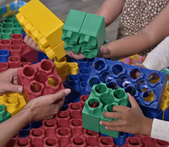 Close-up of hands storing colorful building blocks after a group play session.