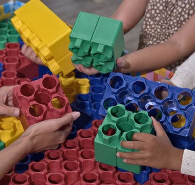 Close-up of hands storing colorful building blocks after a group play session.