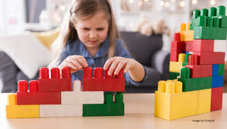 A young girl intensely focused on building a structure with colorful Biggo Blocks, demonstrating the benefits of educational play.